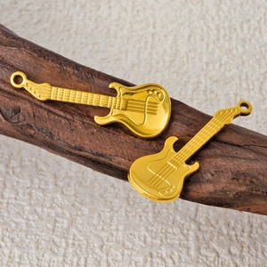 Pair of gold stainless steel guitar pendants for punk hip hop necklaces on wooden surface