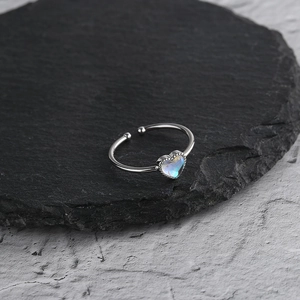 Macro detail of heart-shaped moonstone ring with iridescent glow on dark stone