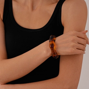 Close-up of wavy amber acrylic cuff bracelet styled on wrist with minimalist aesthetic