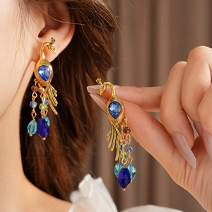 Detail of vintage peacock earrings with blue gemstone and colorful crystal tassel