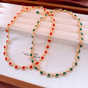 Vintage gold necklace with red and green oval gemstones in a white jewelry box