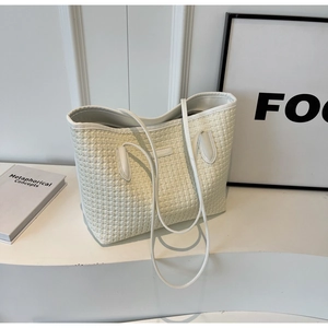 Close-up of minimalist beige woven tote bag with books on a clean white background