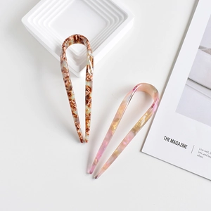 Detail of French tortoise shell and iridescent U-shaped hair pins on a white tray