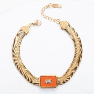 Detail of gold snake chain bracelet with orange stone inlay and sparkling zircon crystal