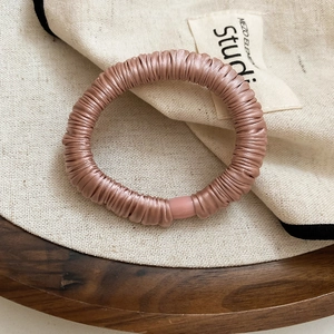 Detail of champagne pink silk scrunchie with soft pleated texture and smooth buckle