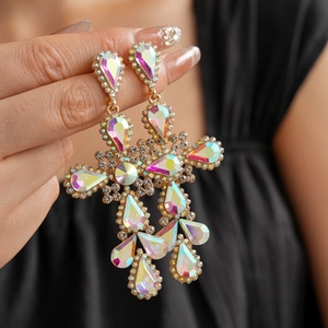 Macro shot of vintage gold cross earrings featuring colorful rhinestones in hand