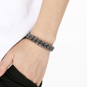 Detailed close-up of vintage engraved punk cuban chain bracelet on a male wrist