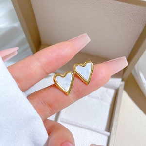 Minimalist gold titanium steel heart earrings with white mother of pearl inlay on finger