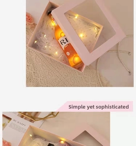 Pink gift box with window, LED fairy lights, white feathers and bottled beverage setup