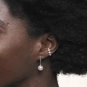 Detail of silver pearl drop earring and cubic zirconia cuff worn on model's ear