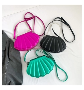 Flachbild von muschelförmigen Handtaschen mit Perlengriffen in Pink, Schwarz und Grün