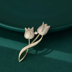 Elegant gold tulip brooch with sparkling pavé crystals on a luxury dark green background