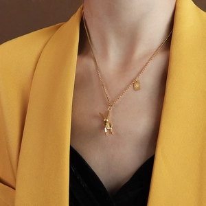Collana chic con ciondolo a forma di coniglio dorato indossata con un blazer giallo