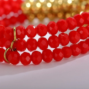 Close-up of vibrant red faceted beads and gold metal rings on a multi-layer bracelet