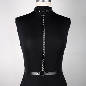 Detail of a black PU leather body harness with silver metal chain and studs on mannequin