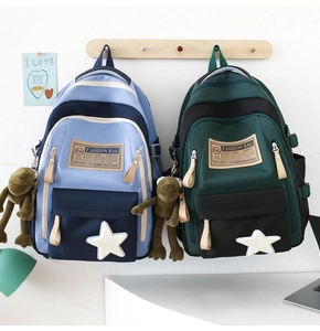 Detail of high-capacity school backpacks in color-block designs with cute plush pendants