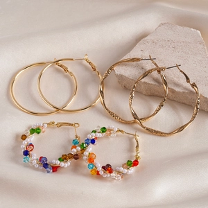 Vue détaillée de créoles dorées et de boucles en perles sur du tissu de soie beige