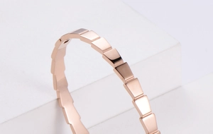 Detail of rose gold geometric faceted bracelet resting on white stones