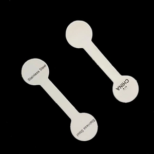 Detailed view of white dumbbell-shaped jewelry tags showing Stainless Steel and origin text