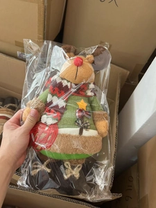 Detail of a Christmas plush reindeer wearing a green knit sweater and plaid scarf