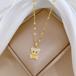 Titanium steel gold teddy bear necklace with white cubic zirconia on a silk background