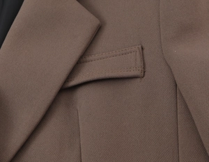 Détail de la texture et des coutures sur la poche et le revers du blazer croisé