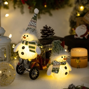 Close-up of lighted plush snowmen with green knit hats on a red vintage truck model