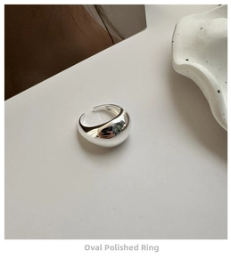 Macro di un anello ovale in argento lucido con design a fascia aperta e regolabile