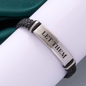 Braided black leather bracelet with silver 'LET THEM' engraved plate on green velvet