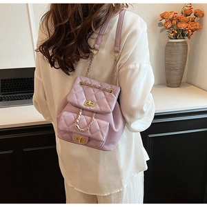 Detail of lavender quilted mini backpack with gold chain strap worn by a model