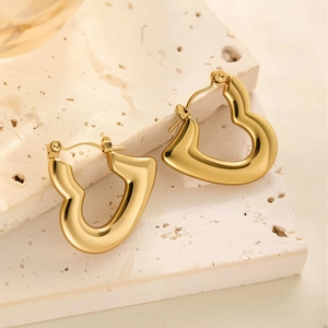 Détail de boucles d'oreilles créoles cœur en acier titane plaqué or 18 carats