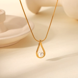 Detail of a golden water-drop pendant with a white pearl on a delicate snake chain