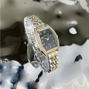 Macro shot of tonneau emerald watch with diamond bezel and bicolor metal strap