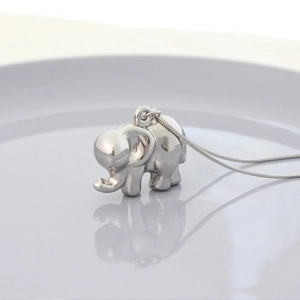 Polished stainless steel elephant pendant necklace on grey ceramic plate