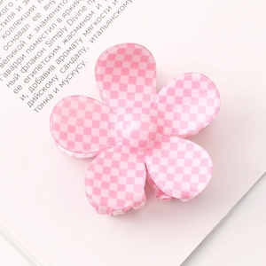 Close-up of pink checkered flower hair claw clip resting on an open book page
