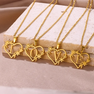 Dettaglio delle collane a cuore con lettere e motivi floreali su base di pietra