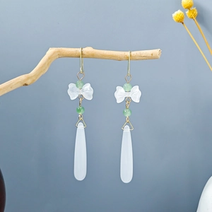 Detail of vintage flower tassel earrings with white bow and green beads on wood branch