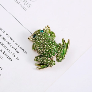 Close-up of a green frog brooch with gold spots and sparkling green gemstone eyes