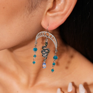 Detail of silver bohemian earrings with crescent moon, black snake, and blue crystal beads
