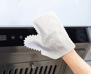 Detail of white non-woven cleaning glove wiping a kitchen range hood control panel