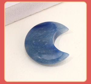 Macro shot of polished blue natural stone moon pendant on a neutral textured background