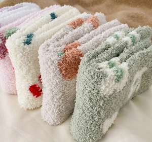 Close-up of thick coral fleece winter socks in soft pastel colors on a cozy surface