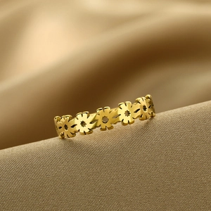 Detailed close-up of golden stainless steel daisy flower ring on silk background