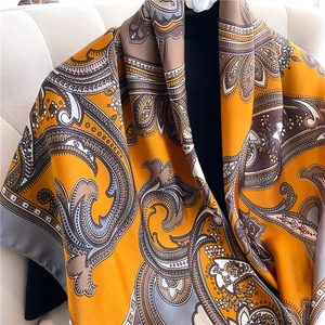 Detail of silk scarf with orange paisley pattern draped on a shoulder to show texture