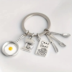 Detailed culinary keychain featuring silver frying pan with egg and mini whisk charms