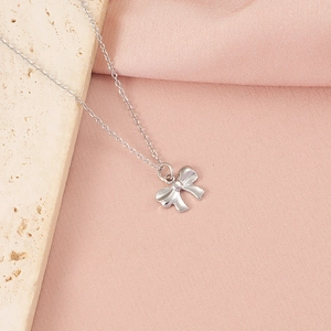 Détail du collier à pendentif nœud argenté posé sur une pierre avec tissu doux