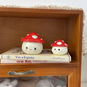Close-up of cute red mushroom desk ornaments with smiling faces on a wooden bookshelf