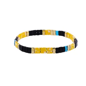 Close-up of bohemian stretch bracelet with yellow, black, and gold Tila enamel beads