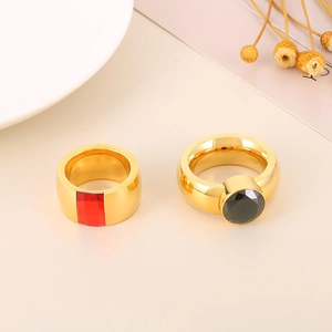 Detail of wide gold-plated rings with red and black geometric zircon stones on a white background