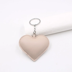 Close-up of beige heart-shaped faux leather keychain with soft texture and refined stitching